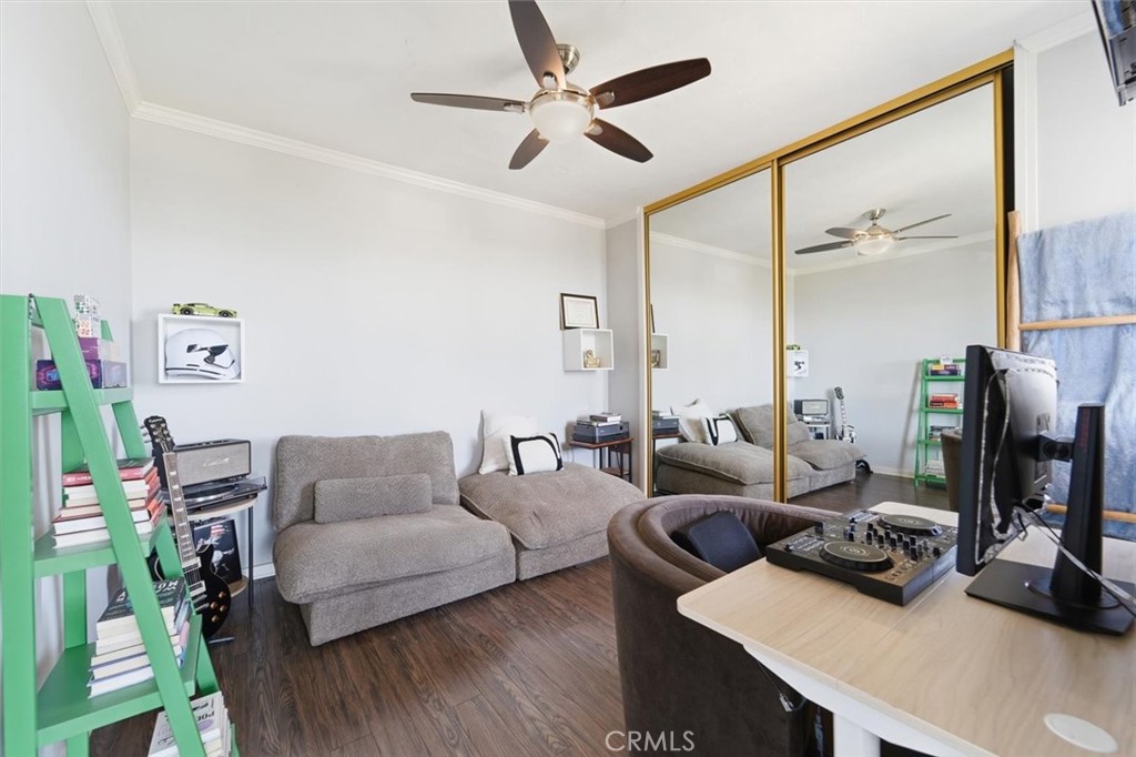 Furnished living room with gray sectional, mirrored closet doors, and DJ equipment.