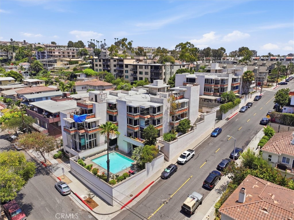 Aerial view of residential buildings around a courtyard pool beside a city street.