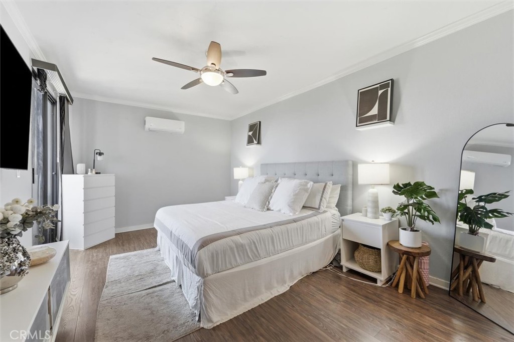 Staged bedroom with a white bed, gray headboard, ceiling fan, and full-length mirror.