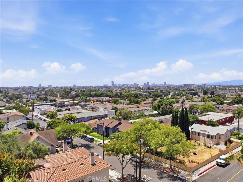 Aerial view over Signal Hill homes toward the distant city skyline.