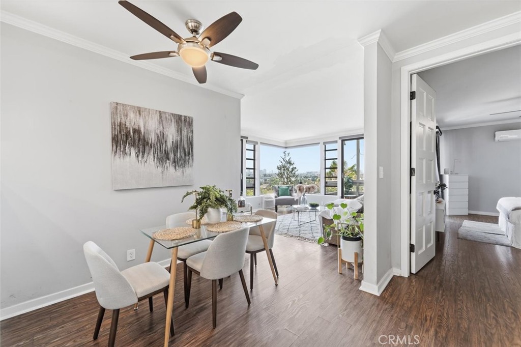 Dining and living area with a glass table, ceiling fan, and corner windows.