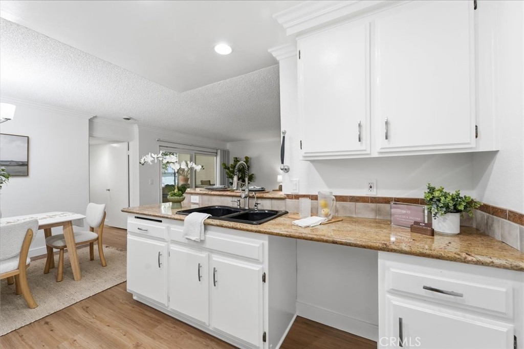 Kitchen with white cabinets, granite counters, a black sink, and an adjoining dining area.