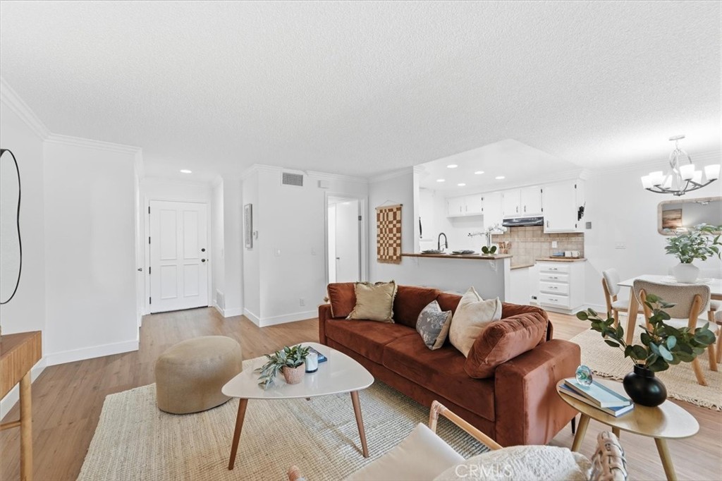 Open-plan living room with a rust-colored sectional, breakfast counter, and adjoining white kitchen.