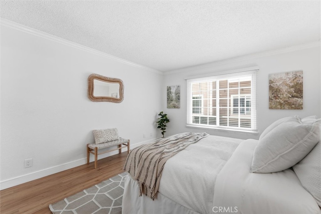 Staged bedroom with a white bed, striped throw, and large window with blinds.