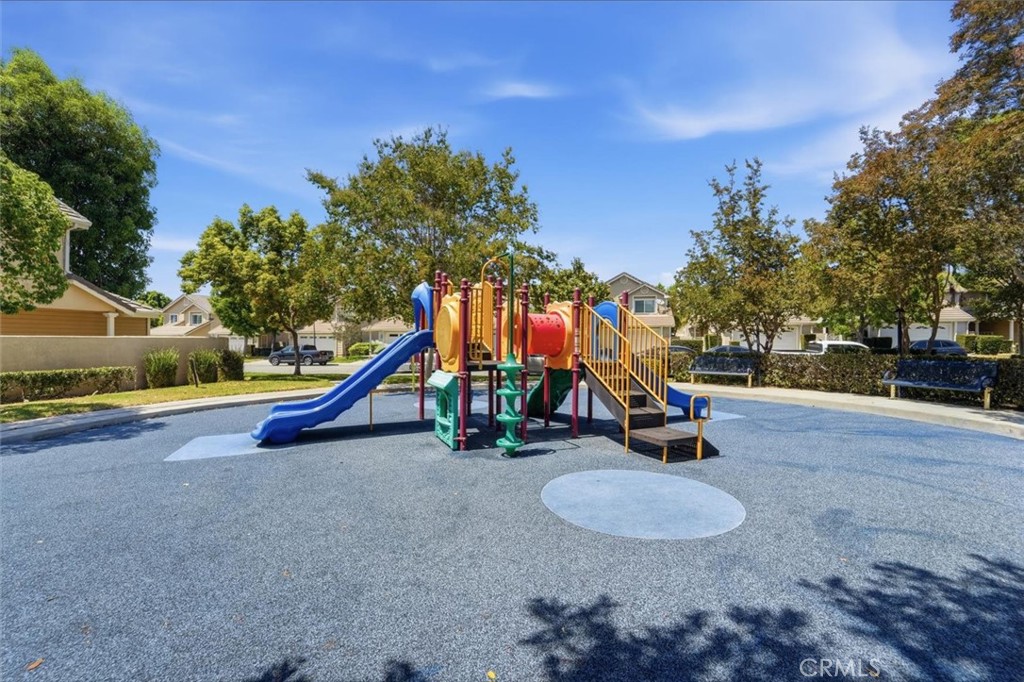Community playground with colorful slides and climbing equipment on a blue safety surface.