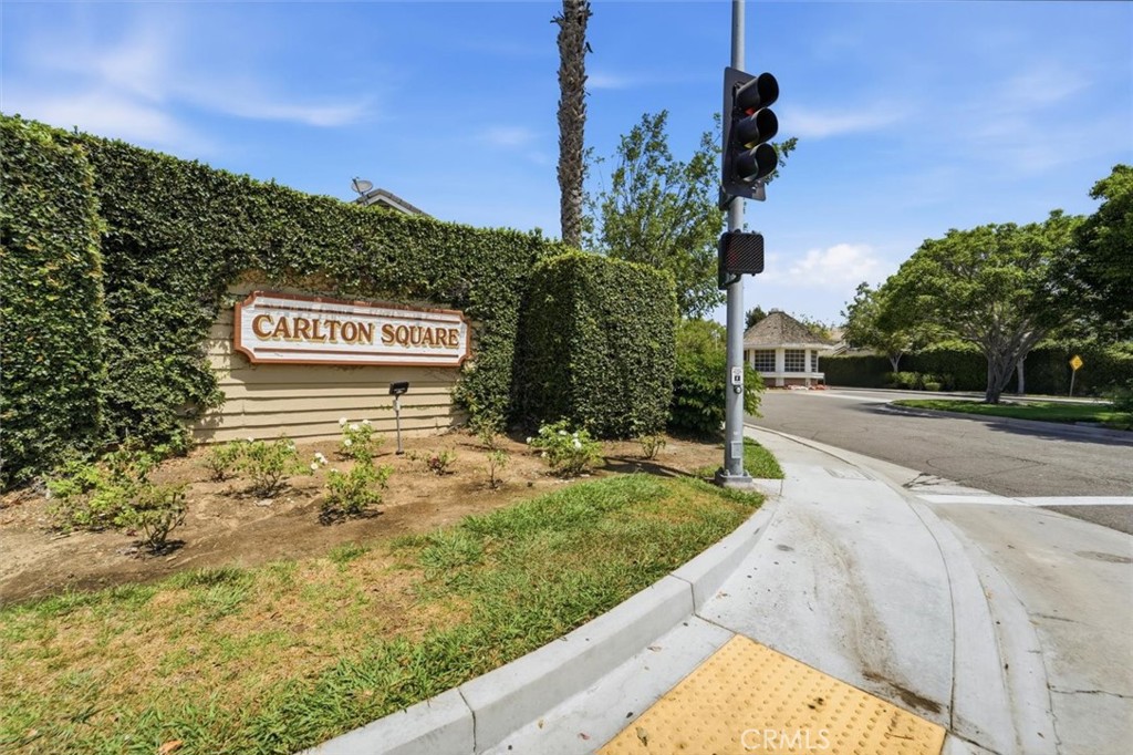 Carlton Square entrance sign beside a tall hedge at a landscaped street corner.