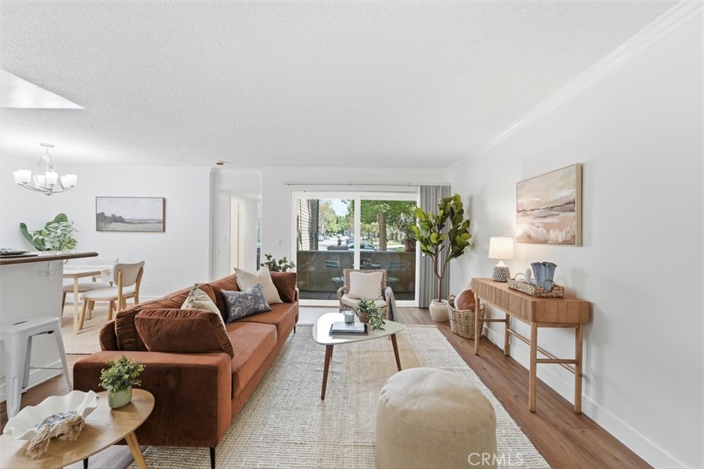 Bright living room with a rust-colored sectional, pale rug, and sliding doors to a tree-lined balcony.