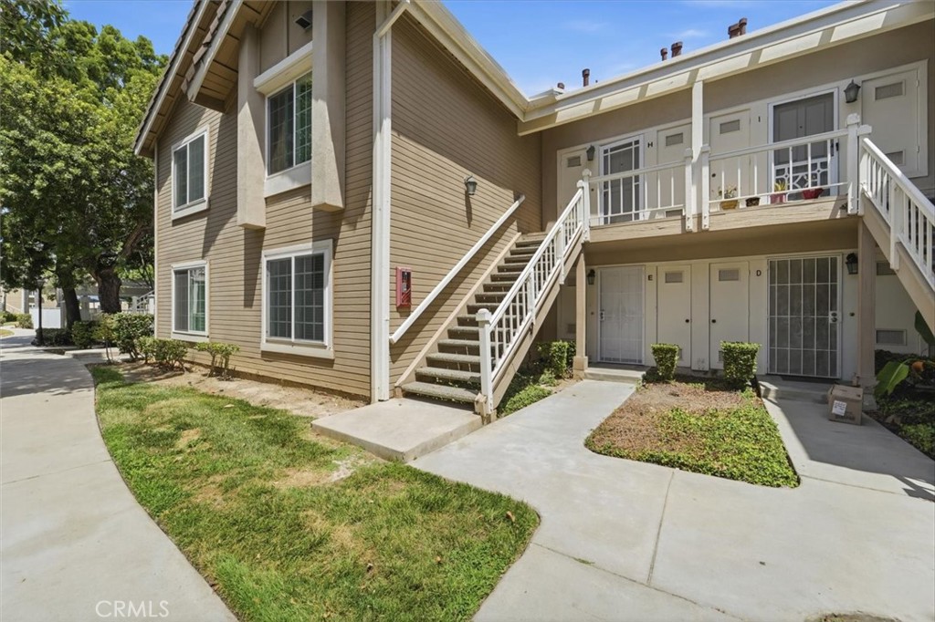 Tan condominium exterior with white staircases, balconies, and landscaped walkways.