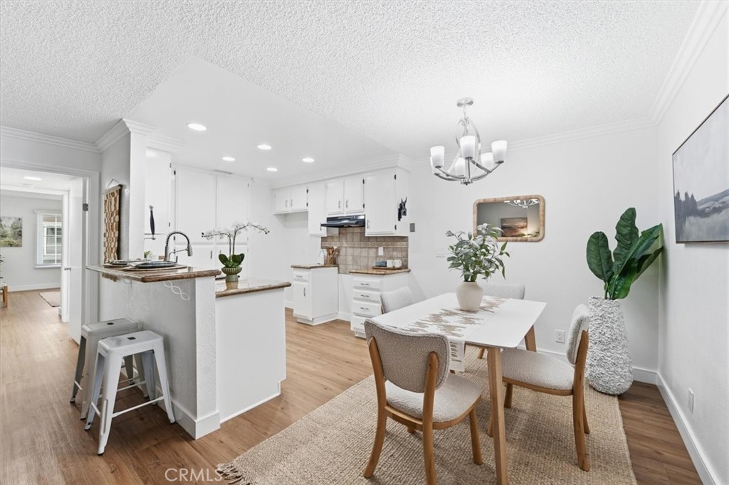 Bright kitchen and dining area with white cabinetry, a breakfast bar, and a table beneath a chandelier.