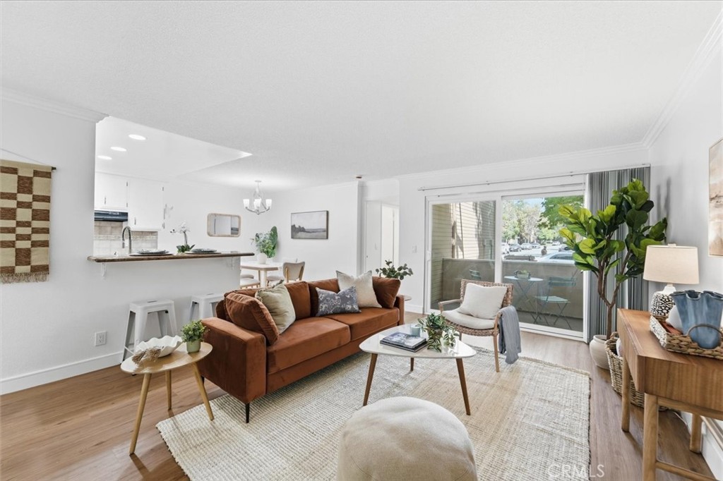Living room with a rust-colored sofa, open kitchen, and sliding glass doors to a patio.