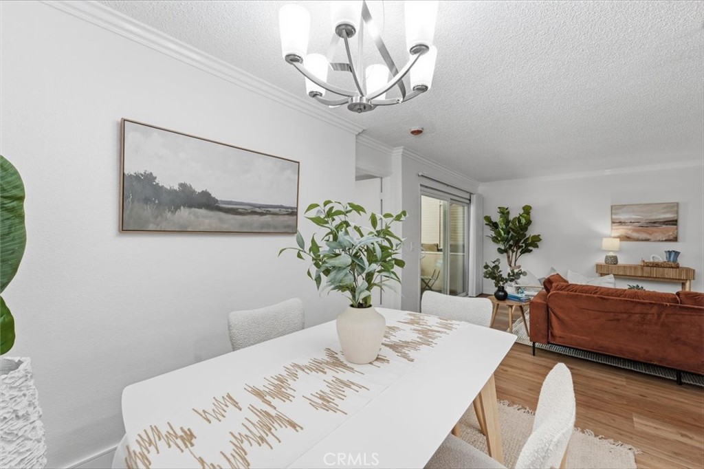 Dining area with a white table and chandelier opening onto a living room with a rust-colored sofa.