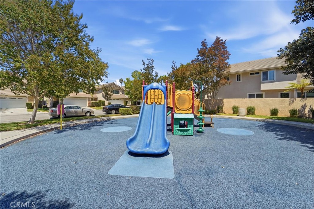 Playground with a blue slide and colorful play equipment on rubber surfacing.