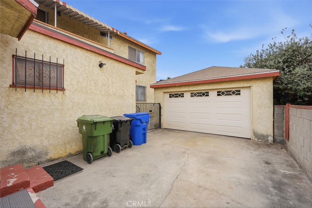 Two-car garage and concrete driveway beside a two-story stucco home.