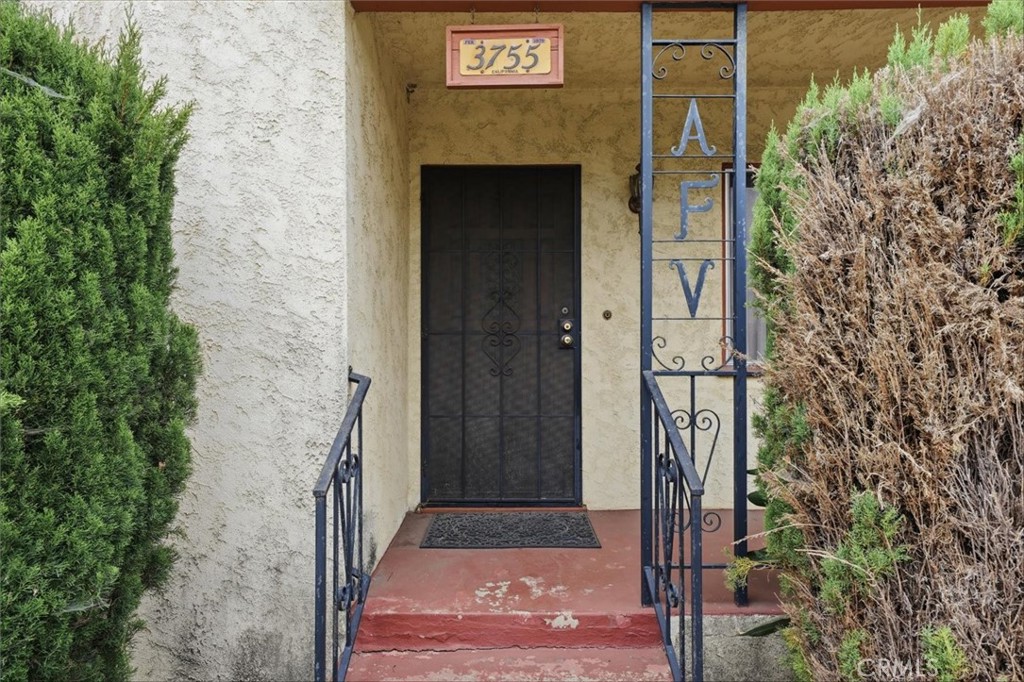Home entrance with a black security door, blue railings, and red-painted steps.