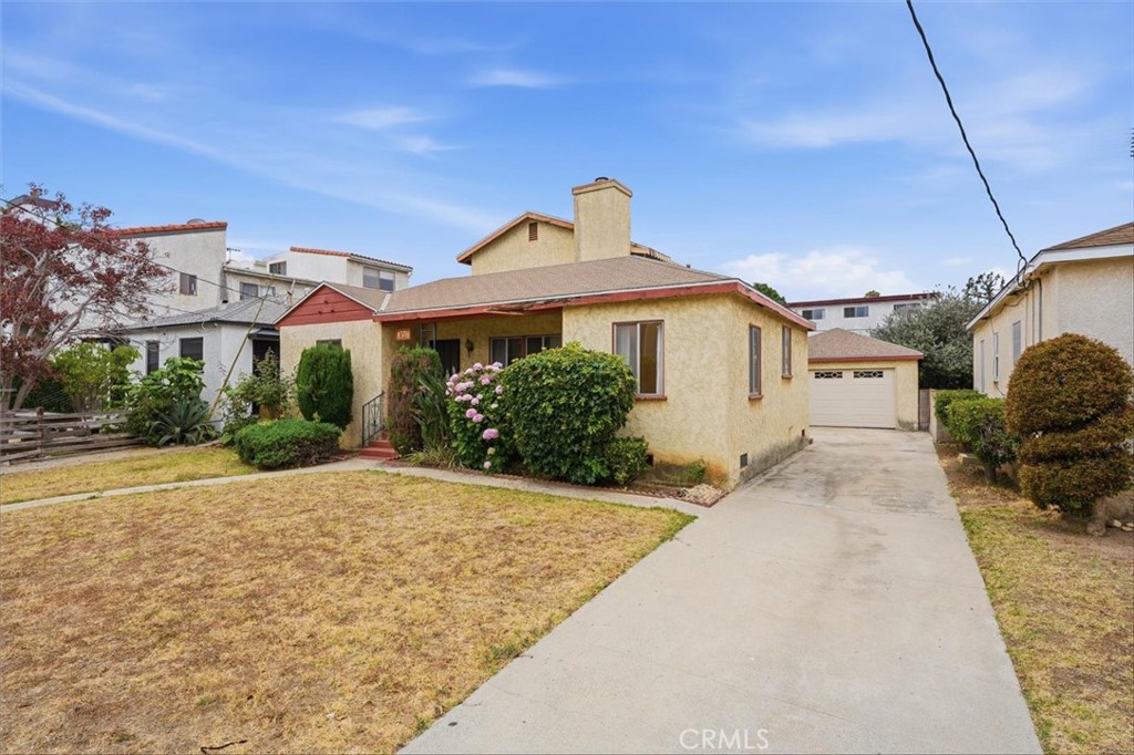Single-story beige house with a red-trimmed roof, attached garage, and concrete driveway.