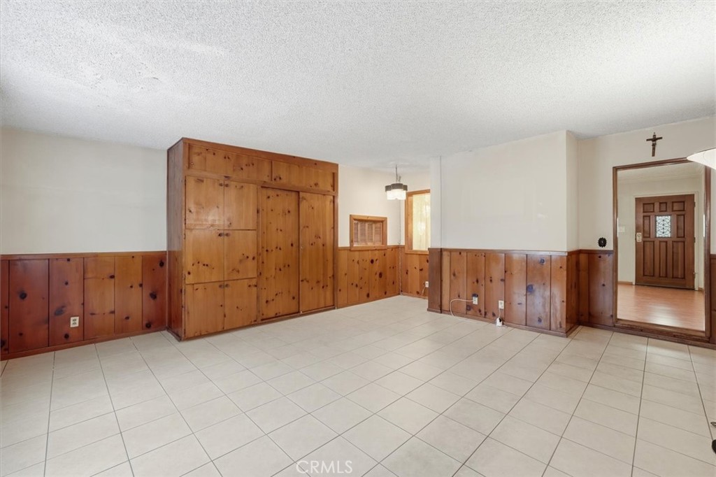 Empty room with tiled floors, wood-paneled walls, and built-in wooden cabinets.