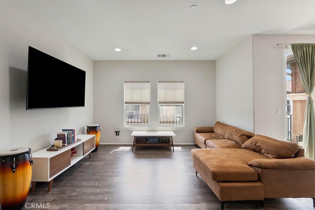 Living room with a brown sectional sofa, wall-mounted television, and two windows.