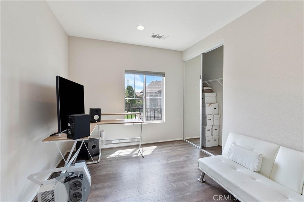 Room with a white sofa, computer desk, and open closet with storage boxes.