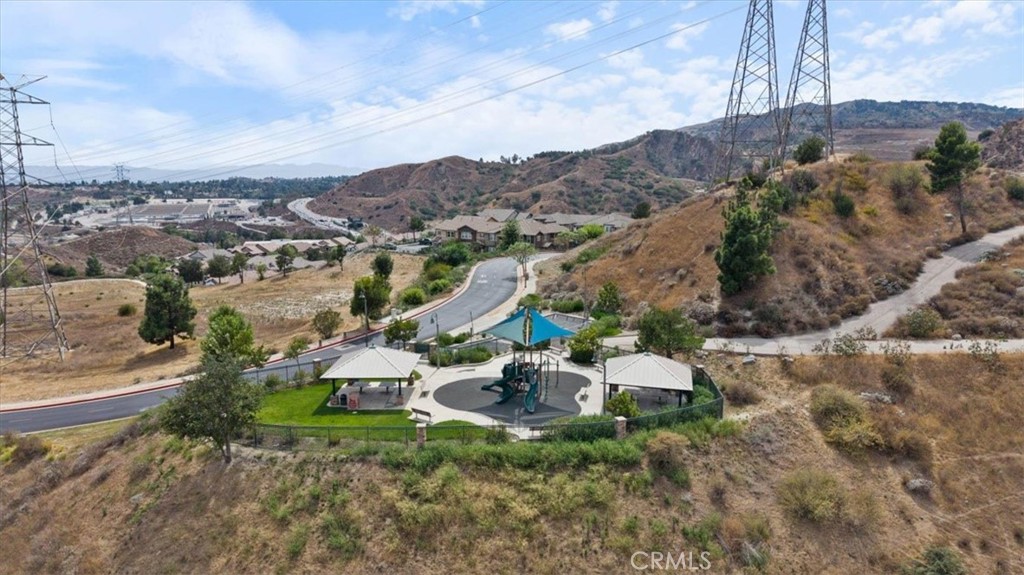 Aerial view of a neighborhood playground with pavilions, a play structure, and dry hills.