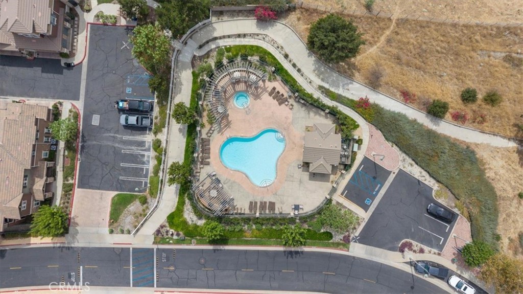 Aerial view of a community pool and circular spa surrounded by lounge chairs and landscaping.