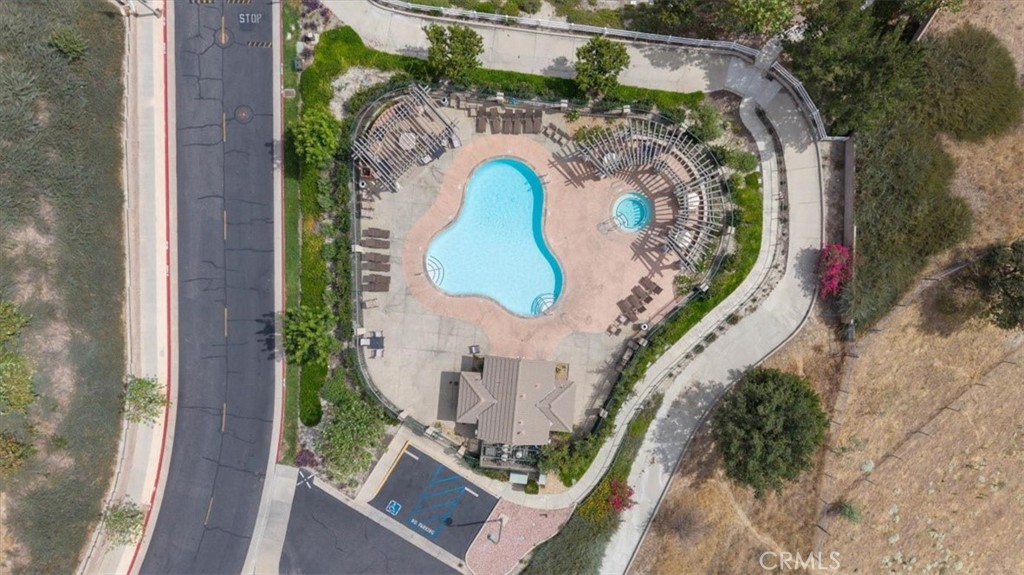 Aerial view of a curving community pool, circular spa, and surrounding lounge deck.