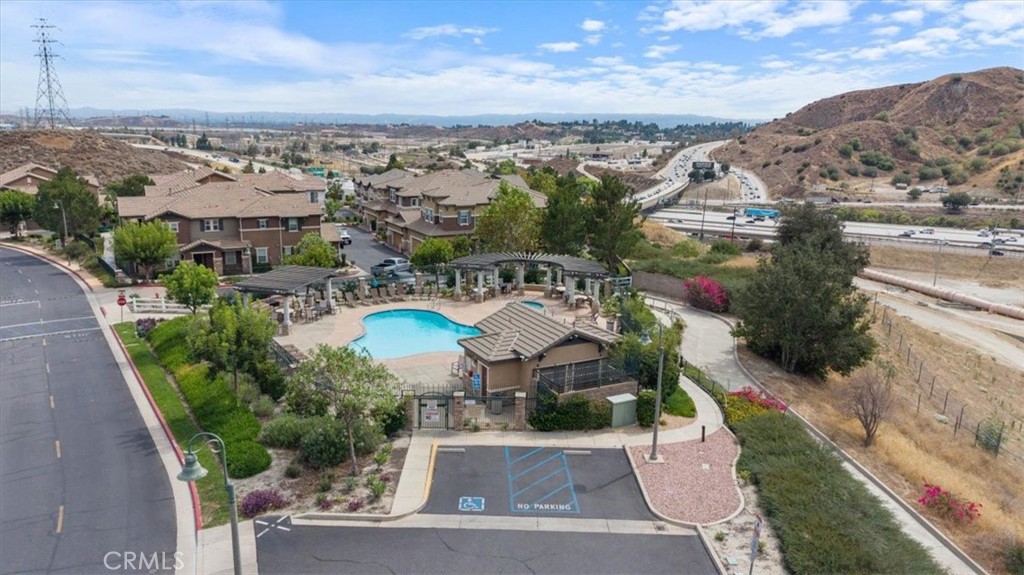 Aerial view of a residential community pool beside homes and surrounding hills.