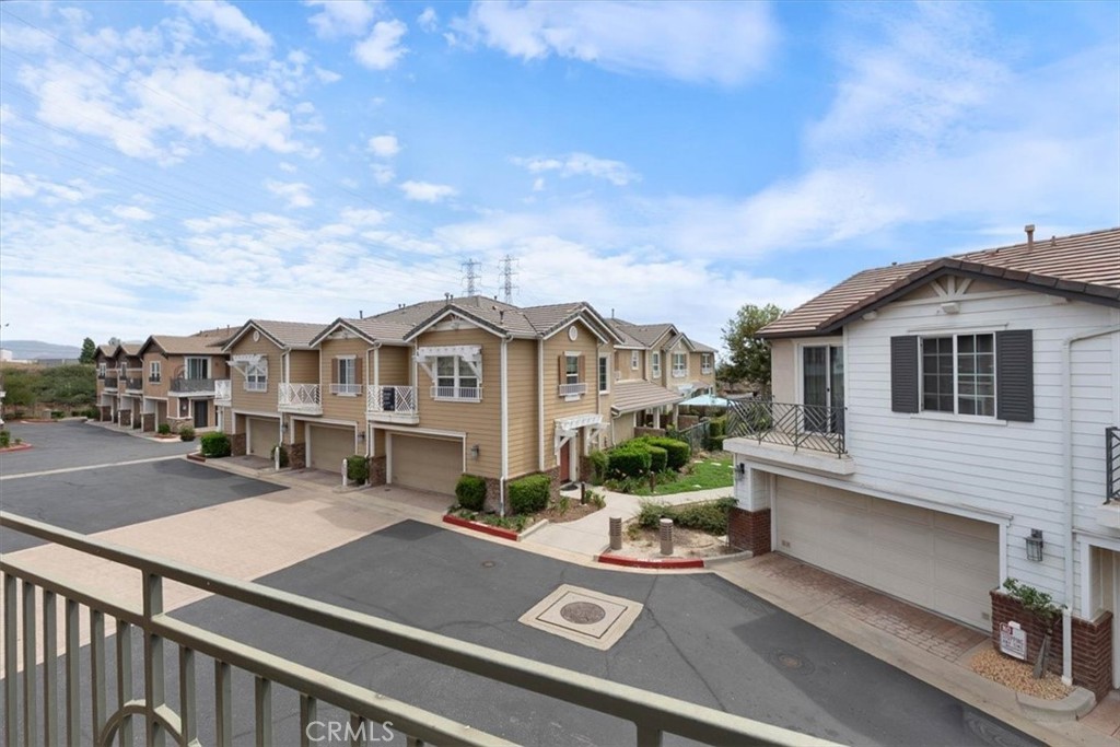 Balcony view across a townhome complex with garages, walkways, and a paved drive.