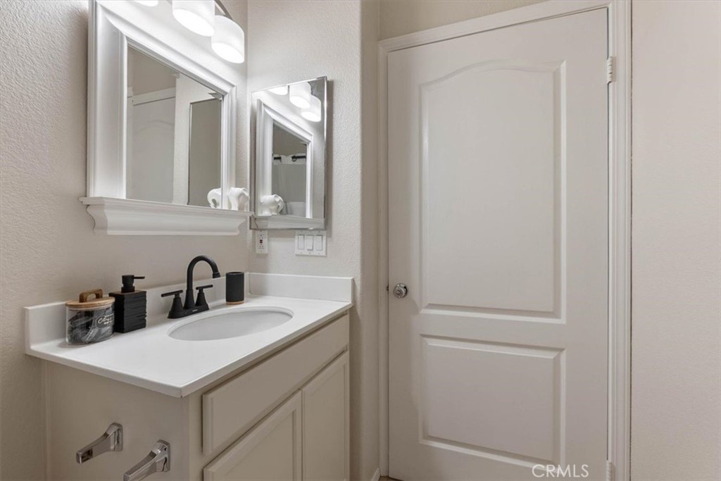 Bathroom vanity with an oval sink, black faucet, framed mirrors, and overhead lights.