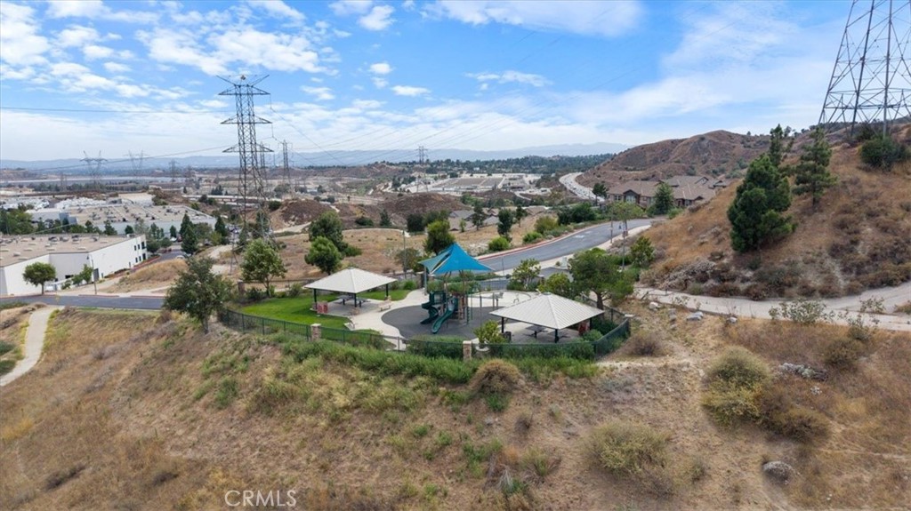 Aerial view of a neighborhood park with a playground and shade pavilions among dry hills.