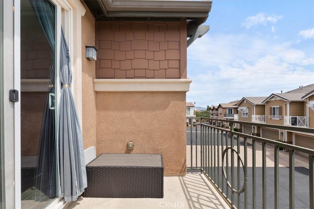 Second-floor balcony with a dark metal railing and neighboring homes in view.