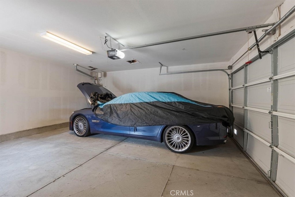 Garage with a blue car partially covered beneath an overhead door.