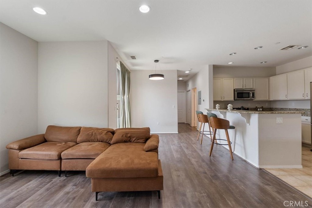 Open-plan living room with a brown sectional and chaise facing a white kitchen island.