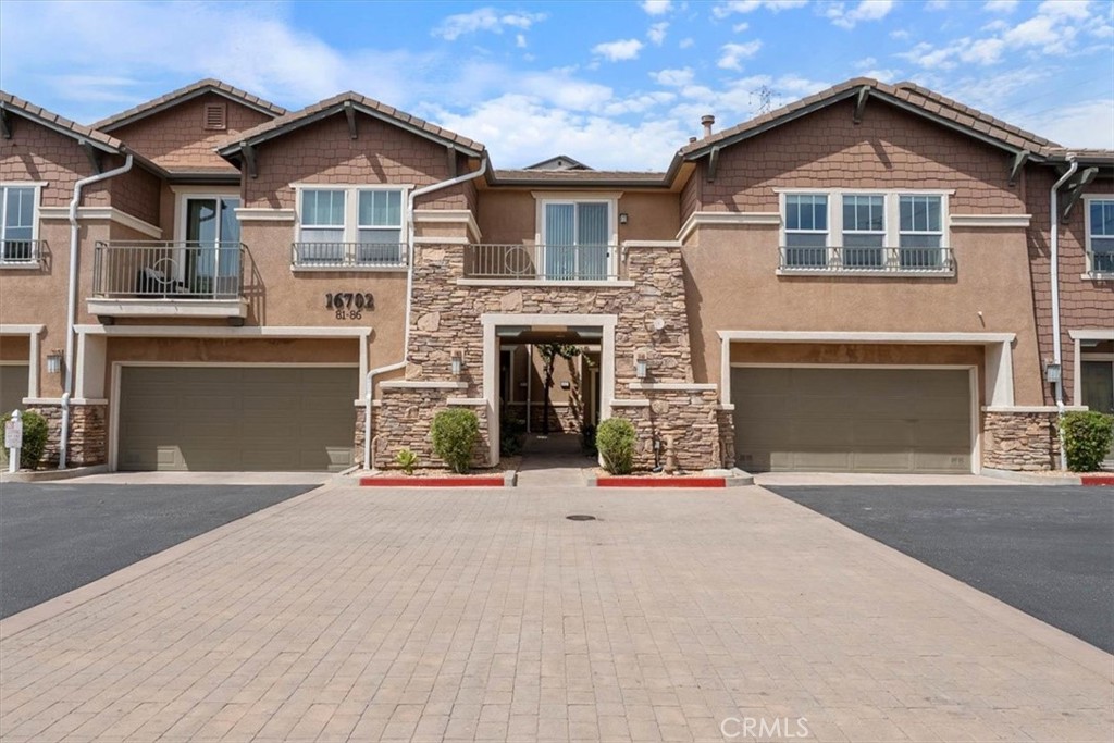 Attached townhomes with a stone-clad entrance, balconies, and two prominent garage doors.