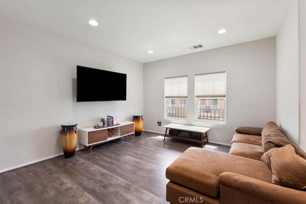 Living room with a brown sectional sofa, wall-mounted television, and two windows.