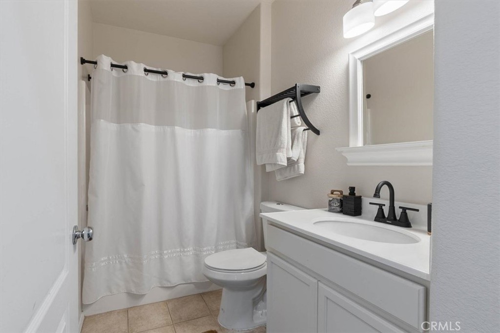 Bathroom with a white vanity, black faucet, and white shower curtain.