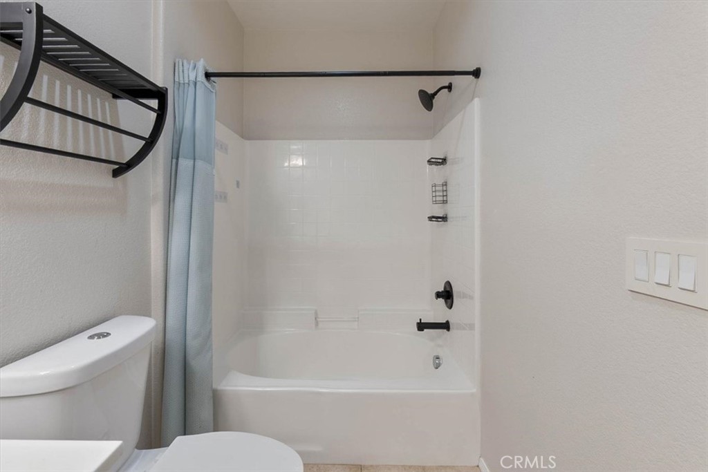 Bathroom with a white bathtub, tiled shower surround, and pale blue curtain.