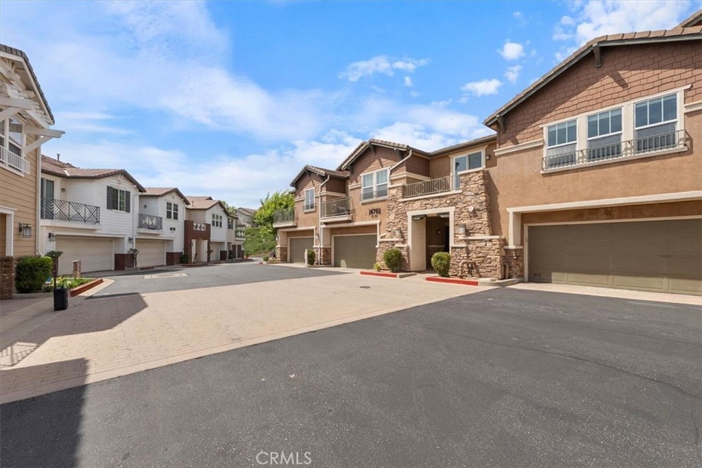 Townhomes with attached garages and balconies lining a shared paved driveway.
