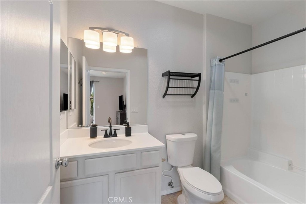Bathroom with a white vanity, oval sink, toilet, and bathtub with a pale blue shower curtain.