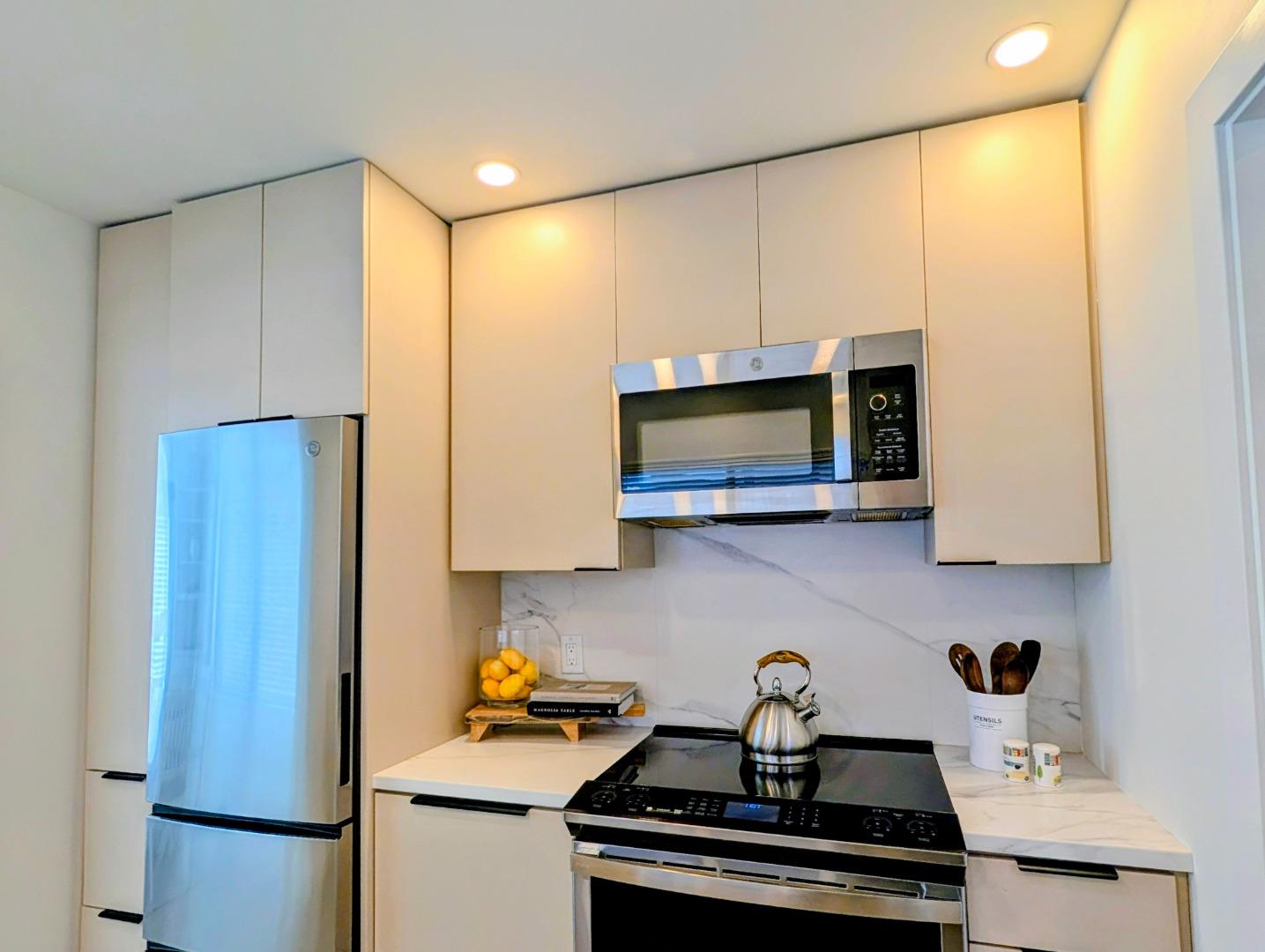 Modern kitchen with white cabinets, stainless appliances, and a marble-look backsplash.