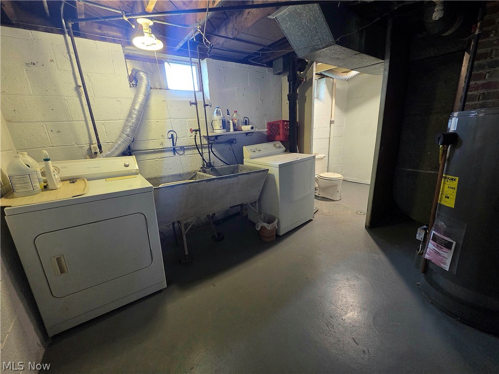 Basement laundry area with washer, dryer, deep utility sink, and toilet in an adjoining alcove.
