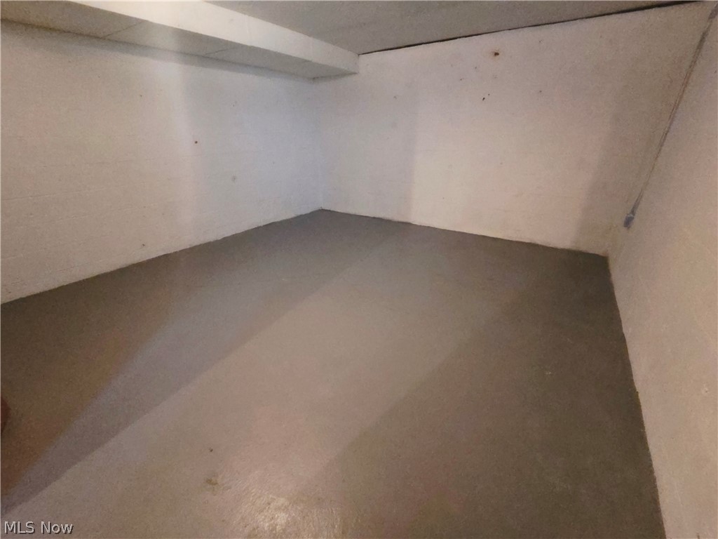 Vacant storage room with a low ceiling, plain walls, and a bare gray floor.