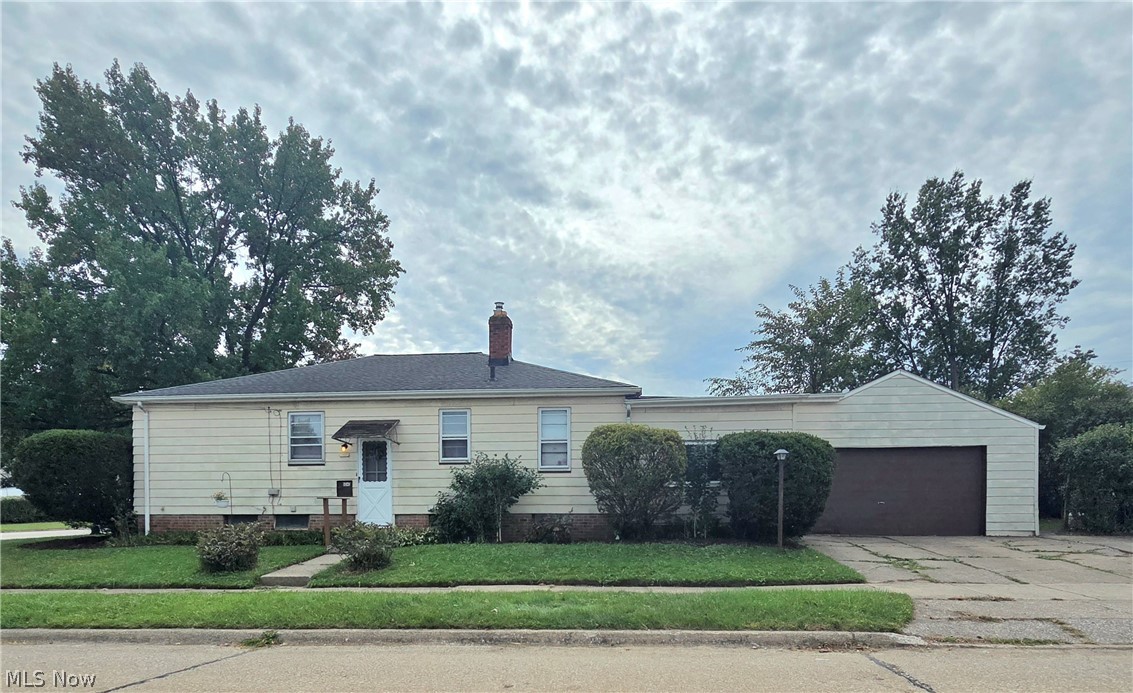 Single-story ranch house with pale siding, brick foundation, and attached garage.