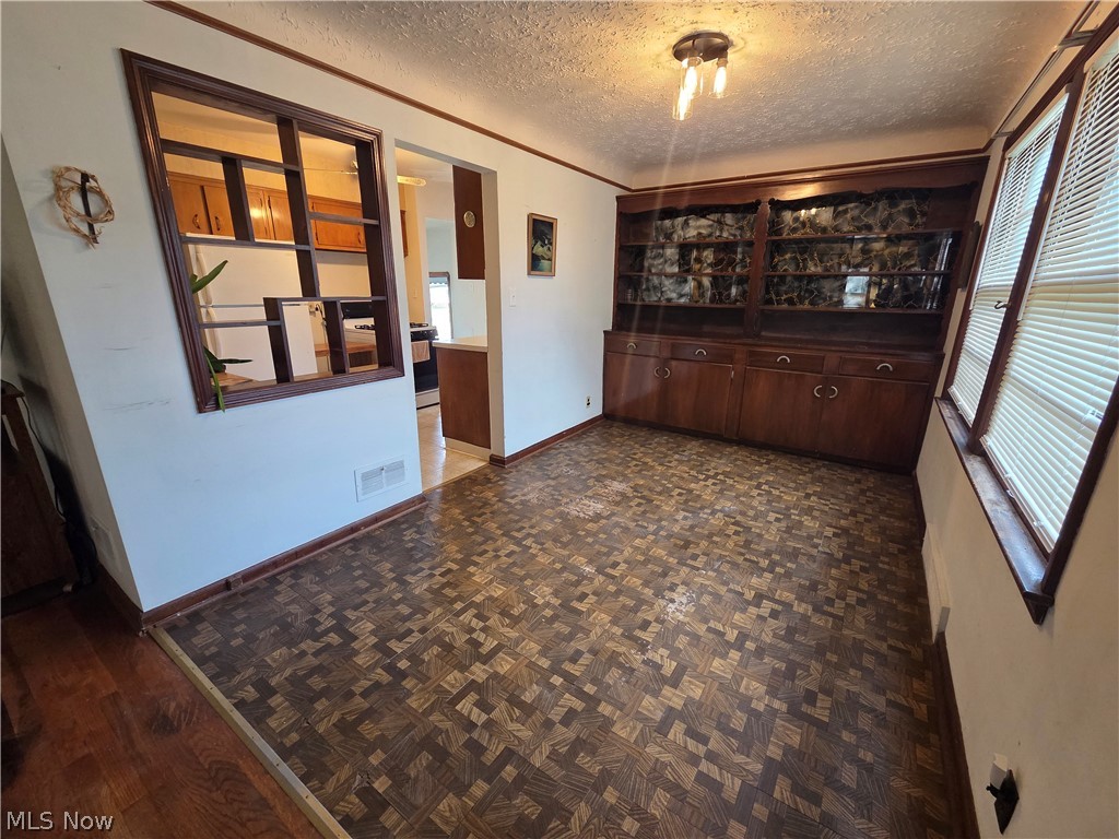 Dining area with patterned parquet flooring, built-in display cabinets, and a pass-through to the kitchen.