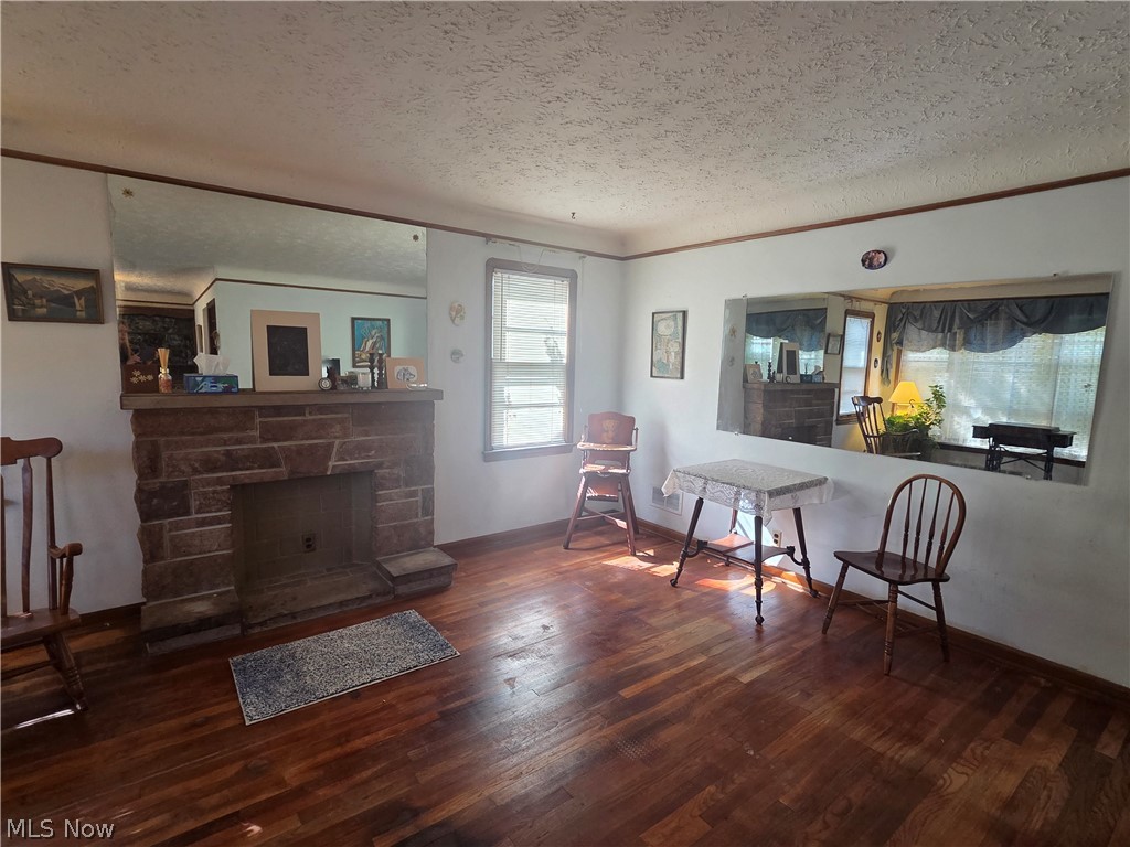 Living room with a stone fireplace, hardwood floors, and a small table with chairs.