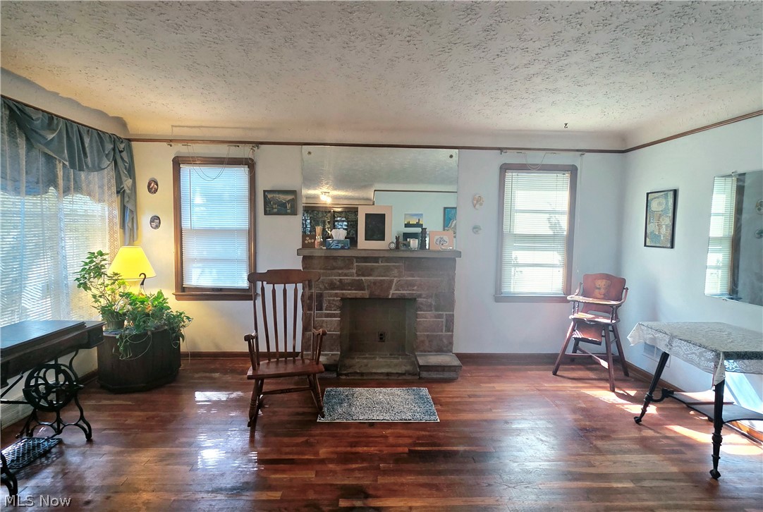 Living room with a stone fireplace, polished hardwood floors, and a wooden rocking chair.