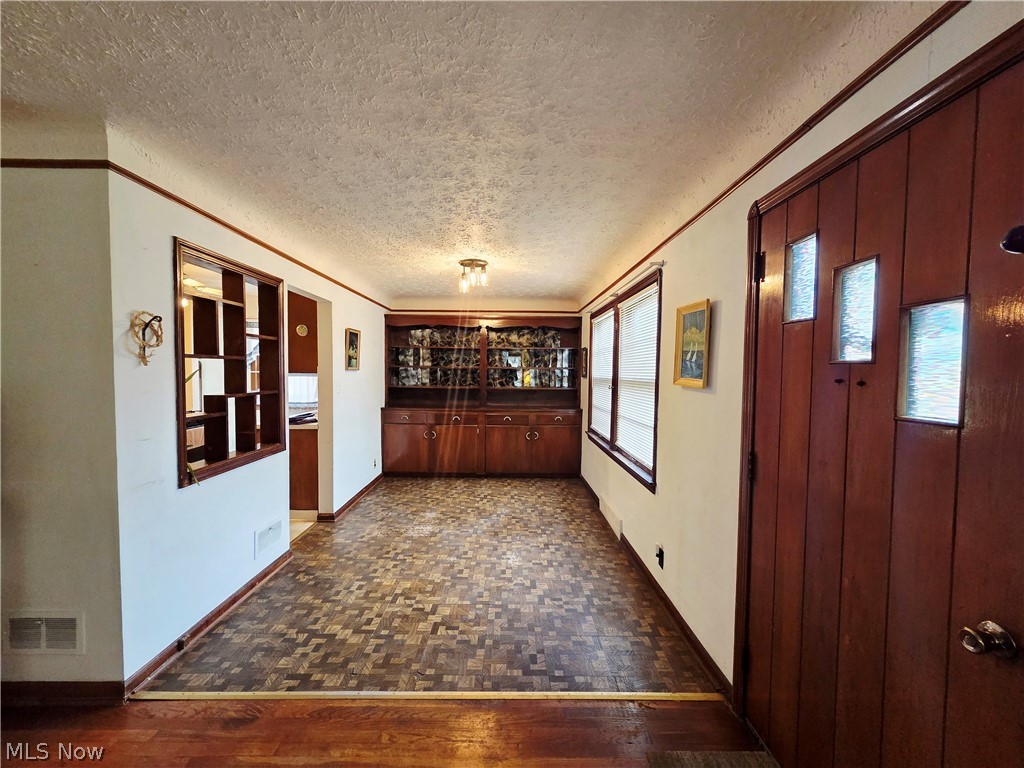 Entryway with parquet flooring, a dark wood front door, and a built-in cabinet.