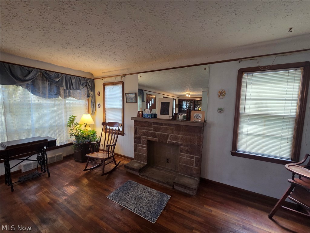 Living room with a stone fireplace, hardwood floors, large windows, and wooden rocking chairs.