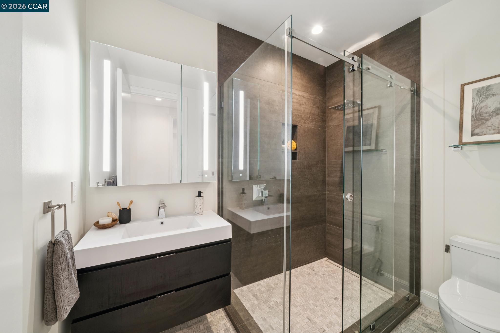 Modern bathroom with a dark floating vanity and a glass-enclosed, dark-tiled shower.