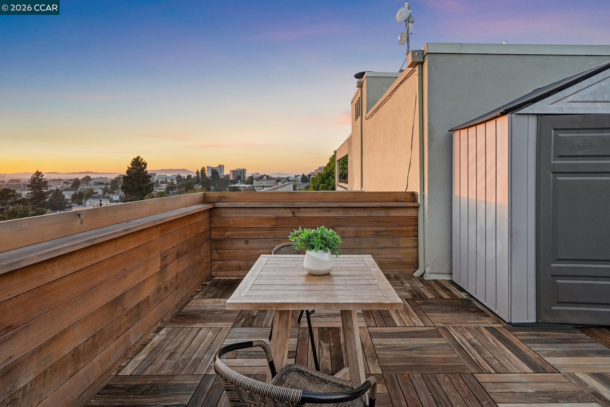 Rooftop terrace with wood decking and city views at sunset.