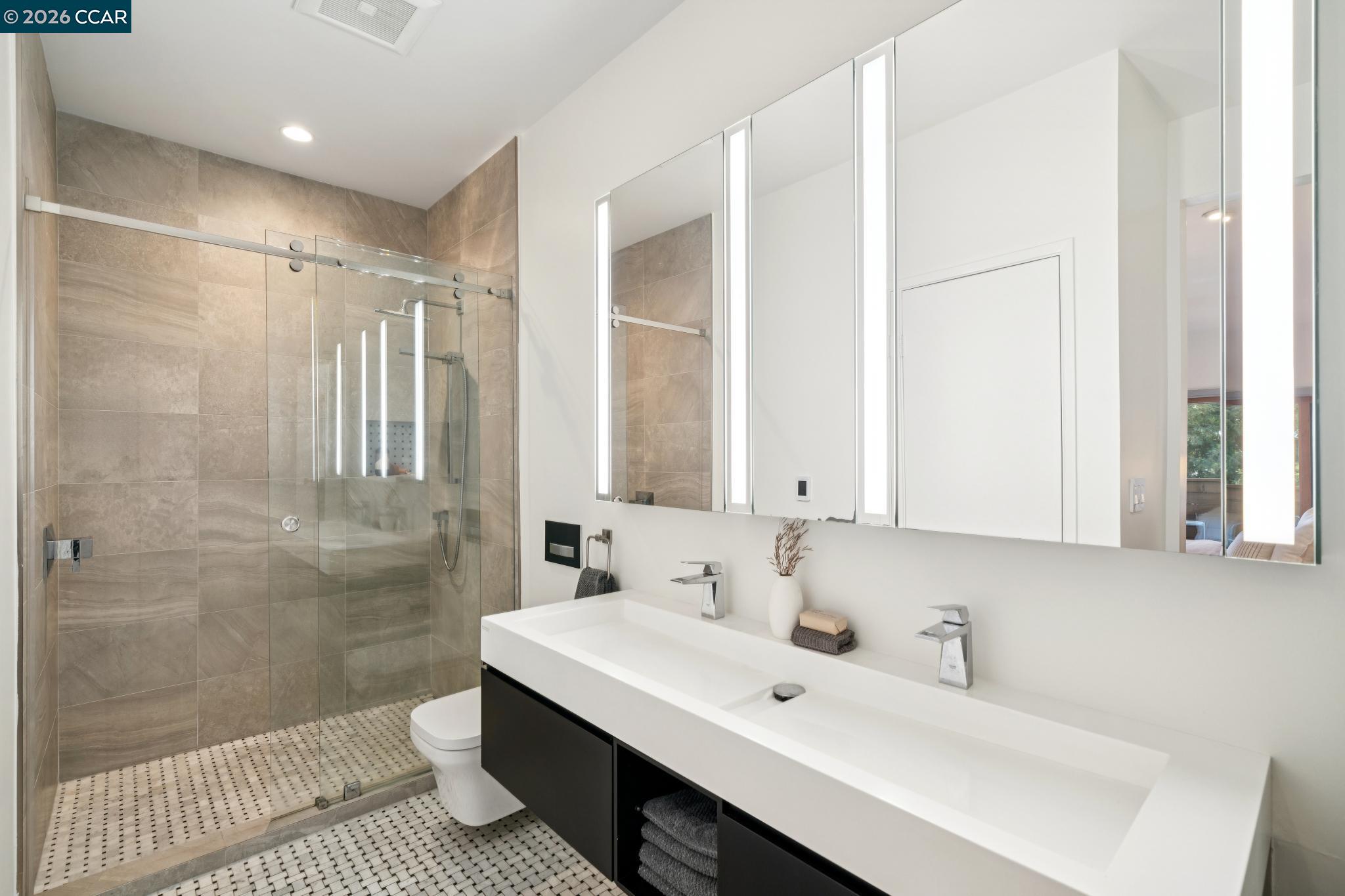 Modern bathroom with a glass walk-in shower and long double-sink vanity.